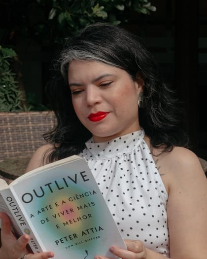 Raisa Arruda lendo um livro de ciência da saúde ao ar livre.